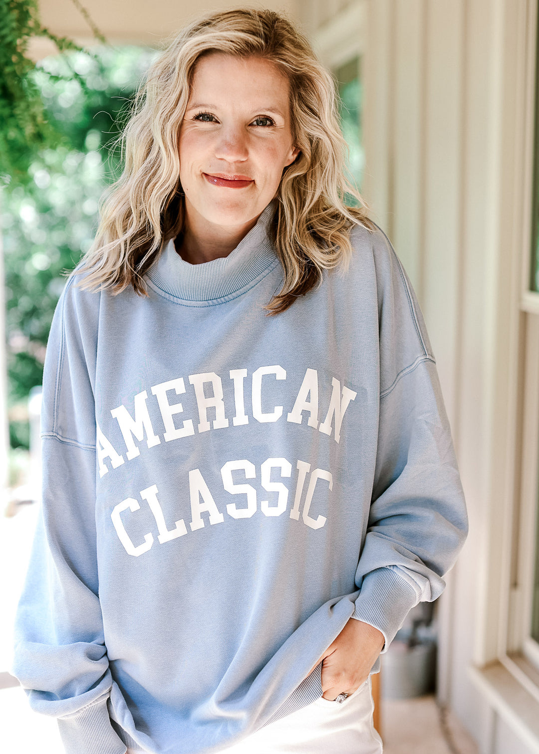 Model wearing a pale blue lightweight sweatshirt with white "American Classic" graphic on front.