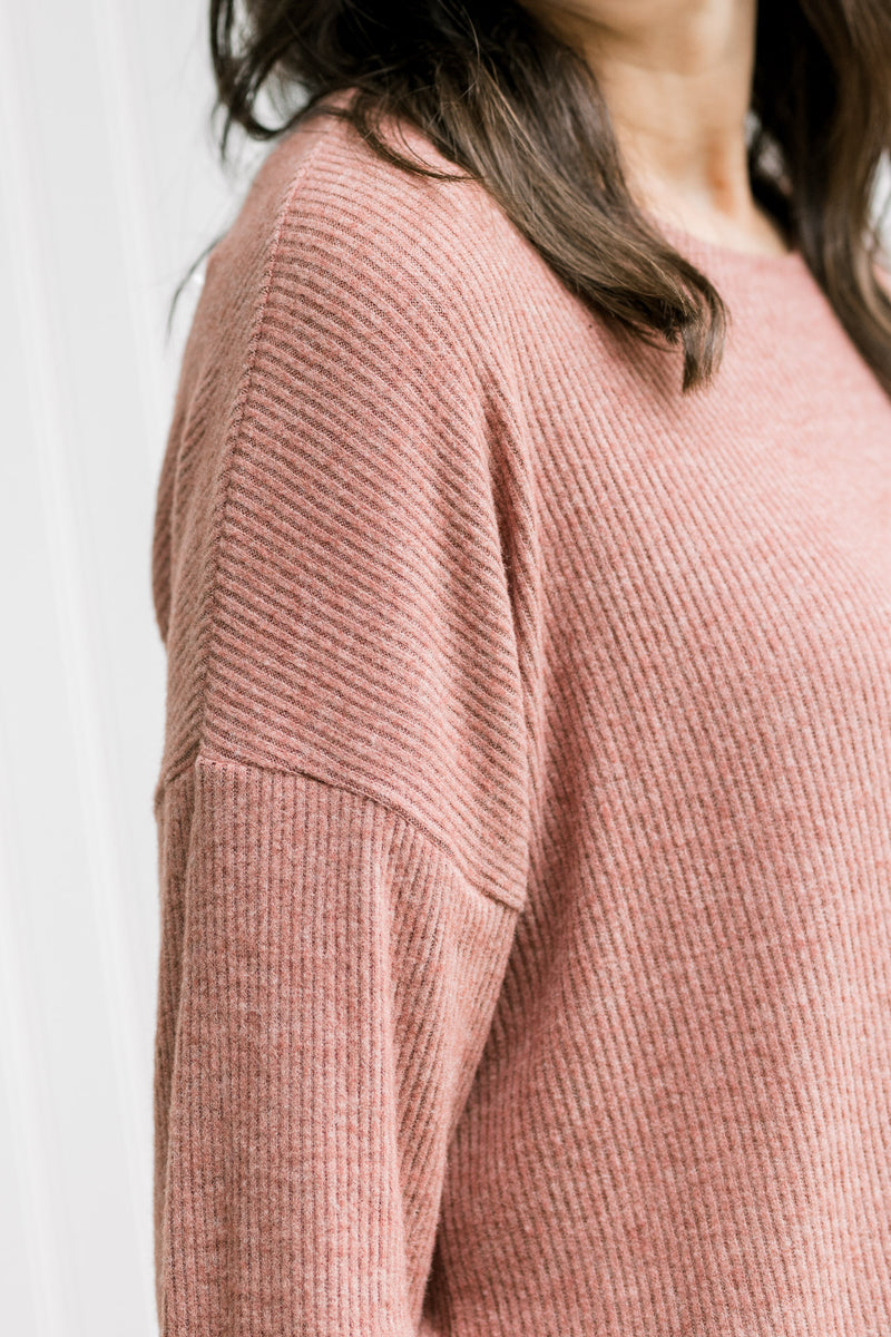 Close up view of ribbed material on a model wearing a wine colored top with long sleeves.