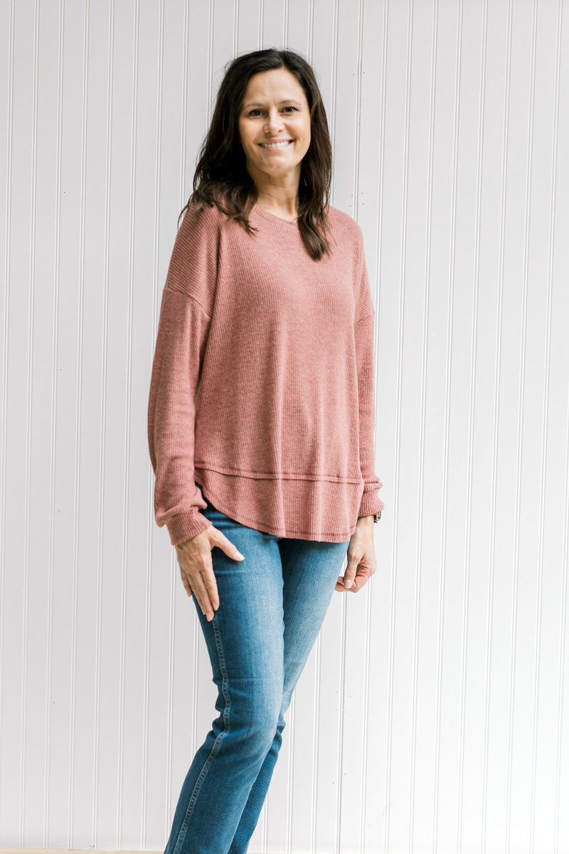 Model wearing a wine colored ribbed top with long sleeves and a round neck.
