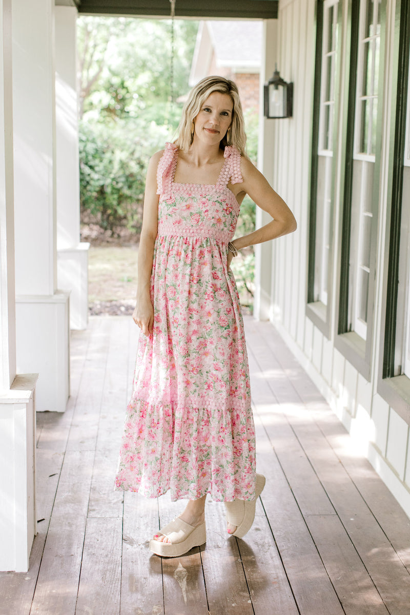 Model wearing wedges with a pink dress with pink and green flowers and tie spaghetti straps.