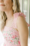Close up of lace tie spaghetti straps on a pink midi with pink and green flowers.