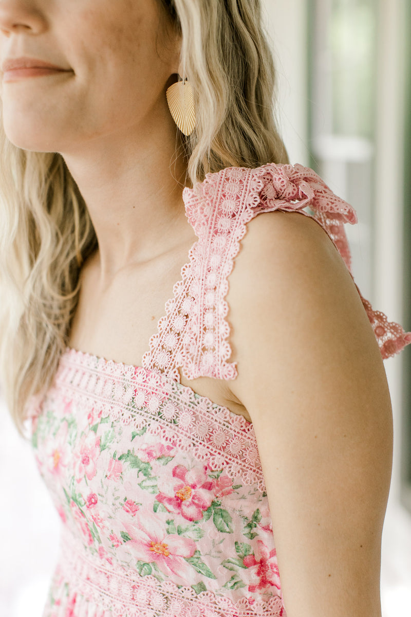 Close up of lace tie spaghetti straps on a pink midi with pink and green flowers.
