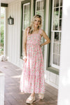 Model wearing a pink dress with pink and green flowers, lace detail and tie spaghetti straps. 
