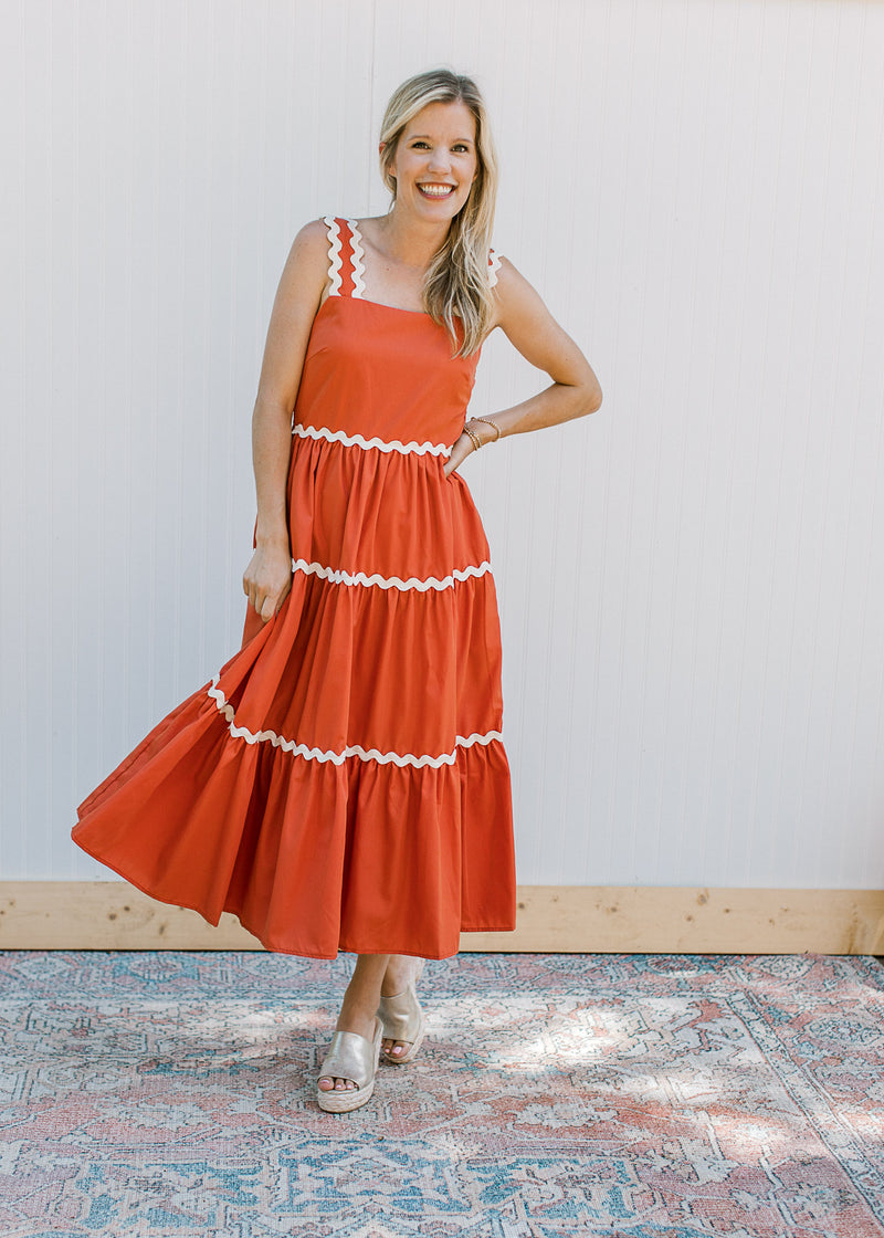 Model wearing a rust dress with ric rac detail at tiers, tank straps and a square neck.