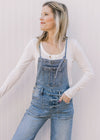 Model wearing light wash overalls with adjustable back tie and a cropped wide leg length.