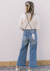 Back view of Model wearing light wash overalls with adjustable tie and a cropped wide leg length.