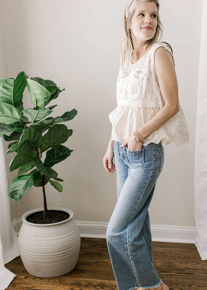 Side view of Model wearing a medium/light wash ankle jeans with a frayed hem.