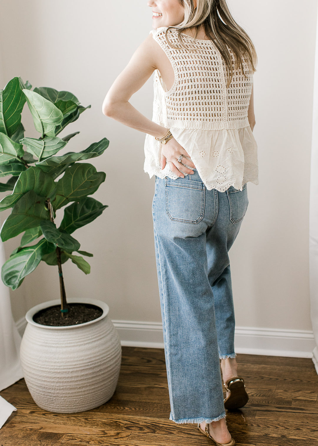 Back view of medium/light wash ankle jeans with high rise, wide leg fit with a frayed hem.