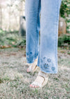 Model wearing medium wash jeans with a cropped wide leg fit and an open cut floral motif at hem. 