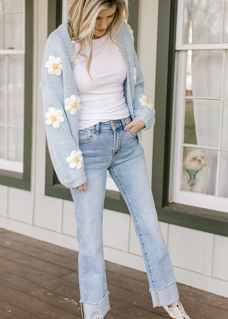 Model wearing blue sweater and light wash jeans with a thick cuff and a straight leg fit. 