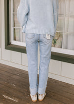 Back view of Model wearing light wash, high rise jeans with a thick cuff and a straight leg fit. 