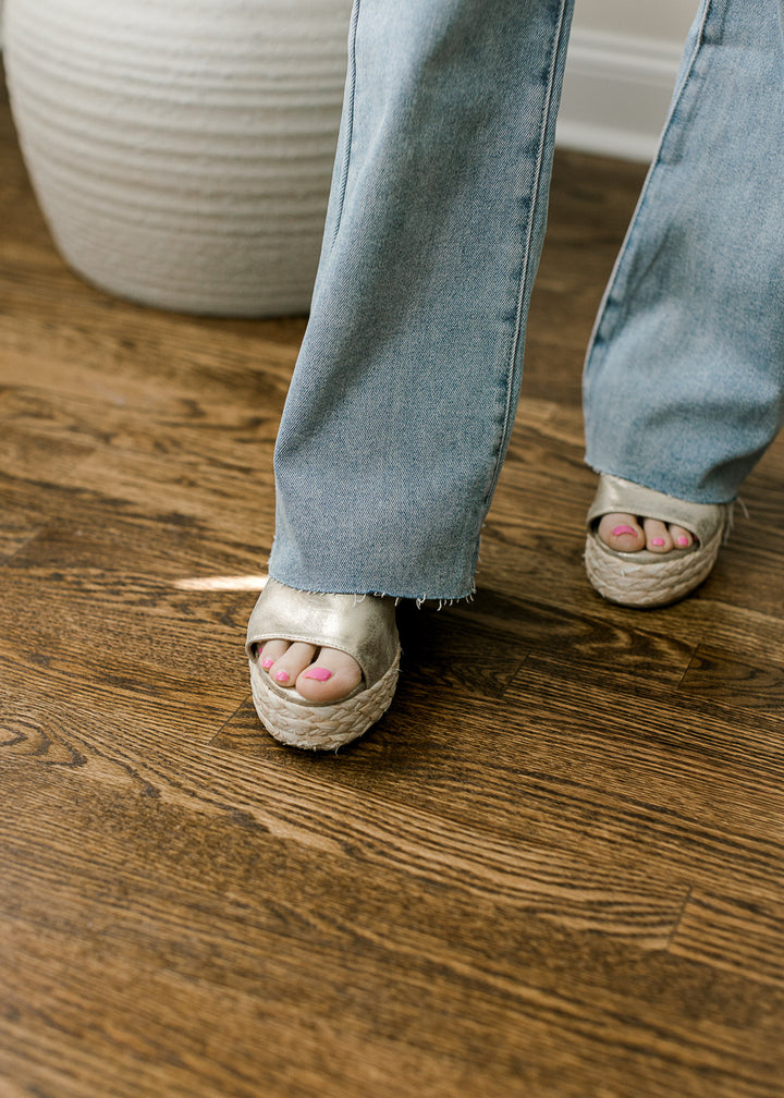 Close up of model in medium/light wash jeans with a raw hemline, and high rise fit. 