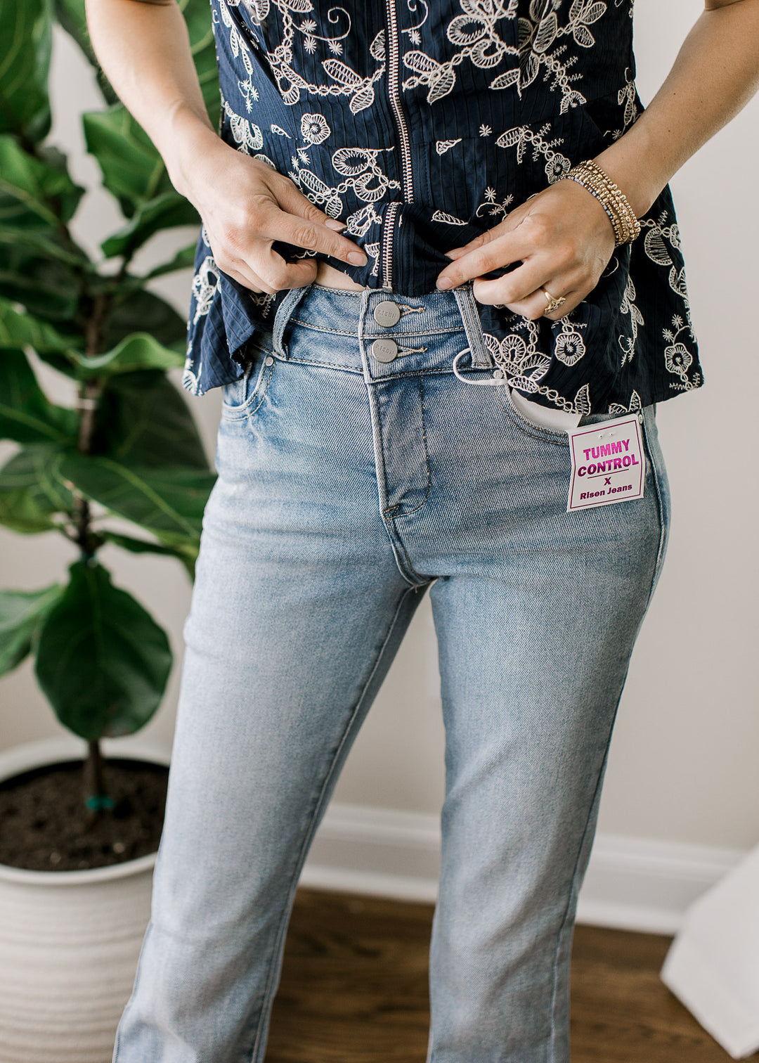 Close up of double button closure on a medium/light wash denim with bootcut fit and high rise. 