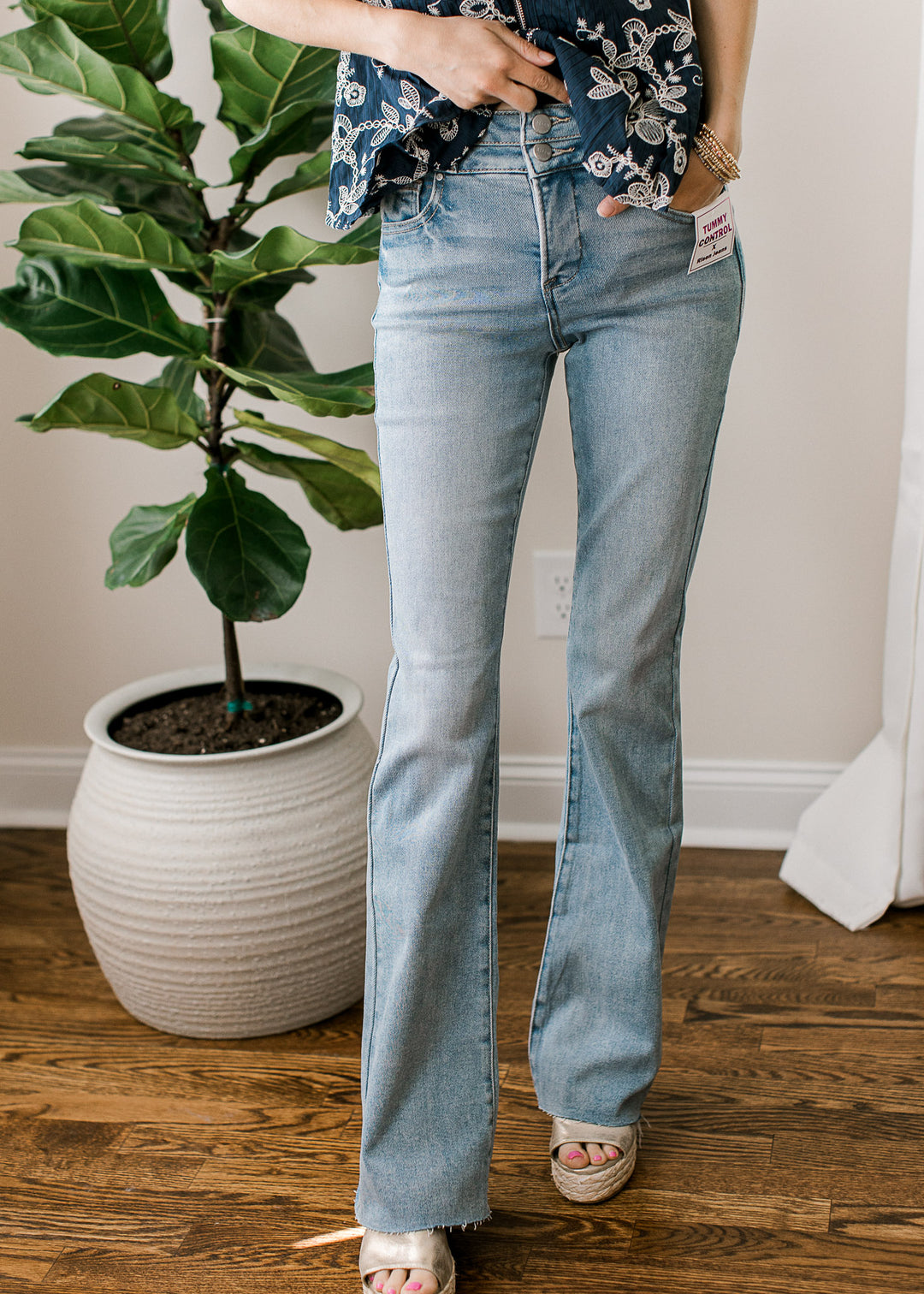 Model wearing heels and medium/light wash jeans with  high rise bootcut fit and a raw hemline. 