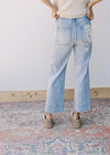 Back view of Model wearing light wash jeans with wide legs and a high waist. 