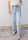 Model wearing light wash jeans with wide legs, button and zip closure and a high waist. 