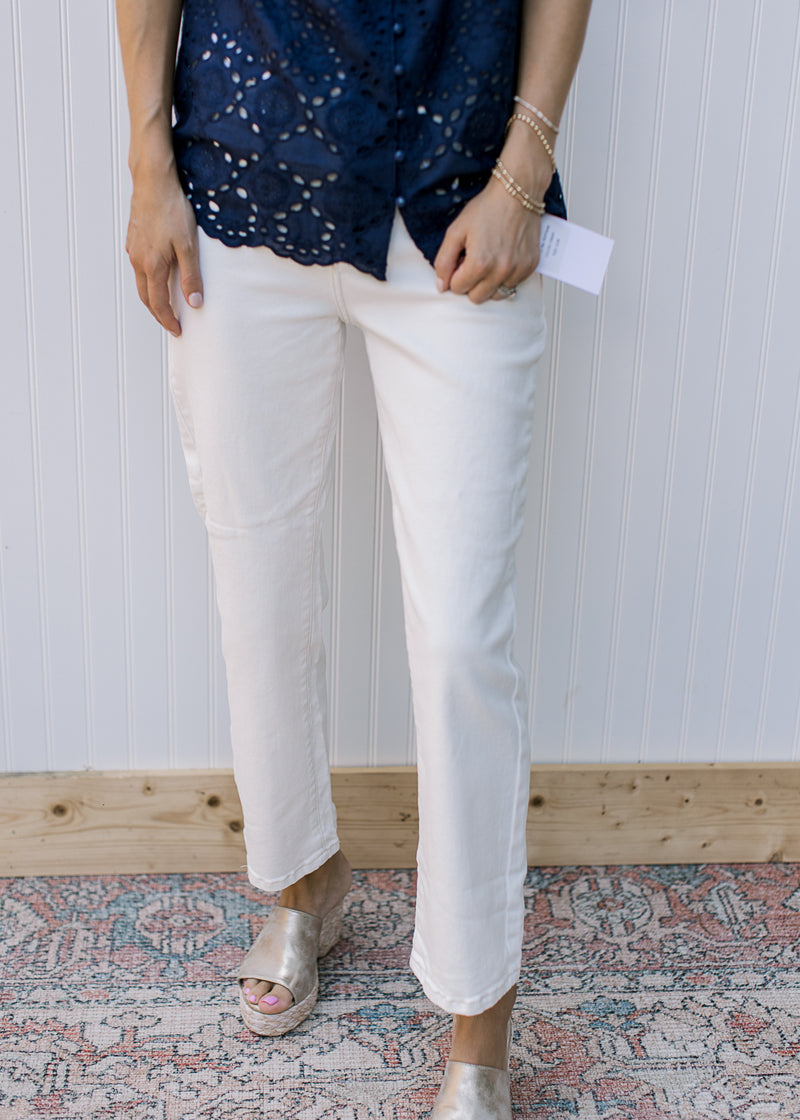 Model wearing a navy top with cream midrise, straight pants with a cropped fit. 