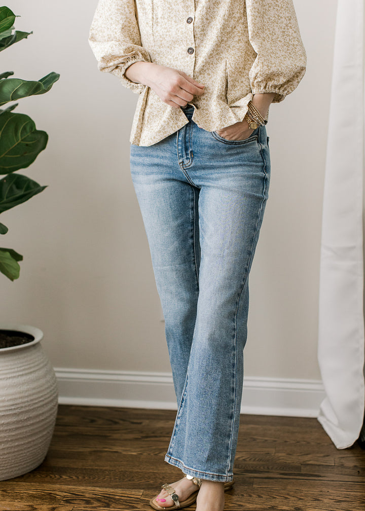 Model wearing a tan top and medium wash jeans with a mid rise, cropped kick flare fit.