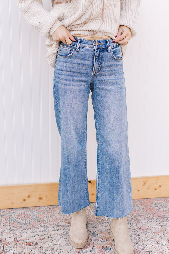 Model wearing tummy control medium wash jeans with soft waistband, wide leg and mid rise fit. 