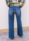 Back view of Model wearing medium wash, wide leg jeans with two button closure and slot pockets.