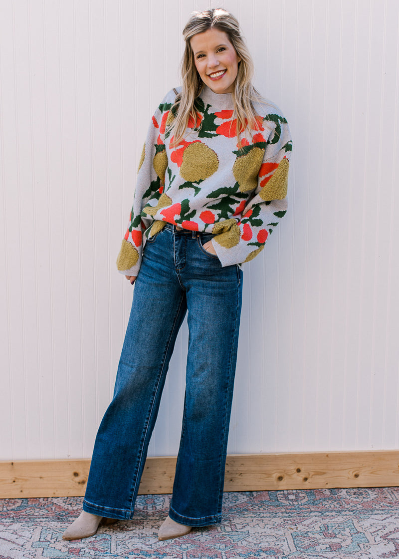 Model wearing a sweater and a medium wash, wide leg jeans with two button closure.