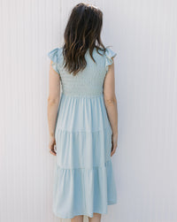 Back view of Model wearing a light blue midi with a smocked bodice and flutter capped sleeves. 