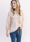 Model wearing jeans with a cream top with russet and green floral v-neck top with 3/4 sheer sleeves.