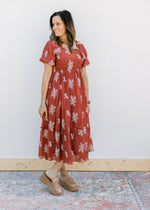 Model wearing wedges and a rust maxi with white embroidered flowers, short sleeves and a square neck