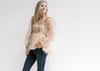 Model wearing jeans with a beige top a rust floral pattern, sheer long sleeves and a square neck.