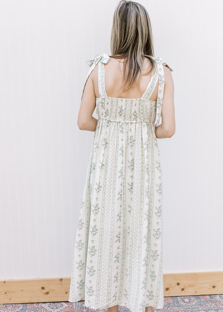 Back view of Model wearing a cream midi with sage floral, adjustable tie straps and smocked back.