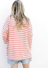Back view of Model wearing a knit cream and rose striped top with side slit and 3/4 sleeves.