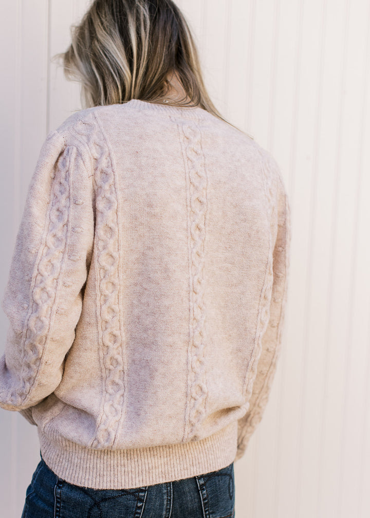 Back view of Model wearing a cream sweater with embossed design, long sleeves and a round neck.