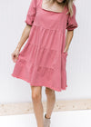 Model wearing a rose colored dress with a frayed hem, square neckline and bubble short sleeves.