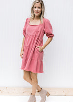 Model wearing a rose dress with pockets, a frayed hem and bubble short sleeves. 
