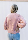 Back view of Model wearing a rose sweater with a mock neck, 3D flowers and long sleeves. 