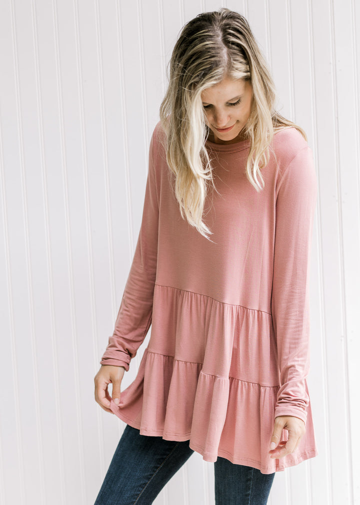 Model wearing a rose colored bamboo viscose top with a tiered design, long sleeves and a round neck.