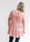 Back view of Model wearing a rose colored bamboo viscose top with a tiered design and long sleeves. 