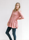 Model wearing jeans with a rose colored bamboo viscose top with a tiered design and long sleeves. 