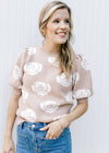 Model wearing a soft pink sweater with cream roses, pleated shoulders and bubble short sleeves.