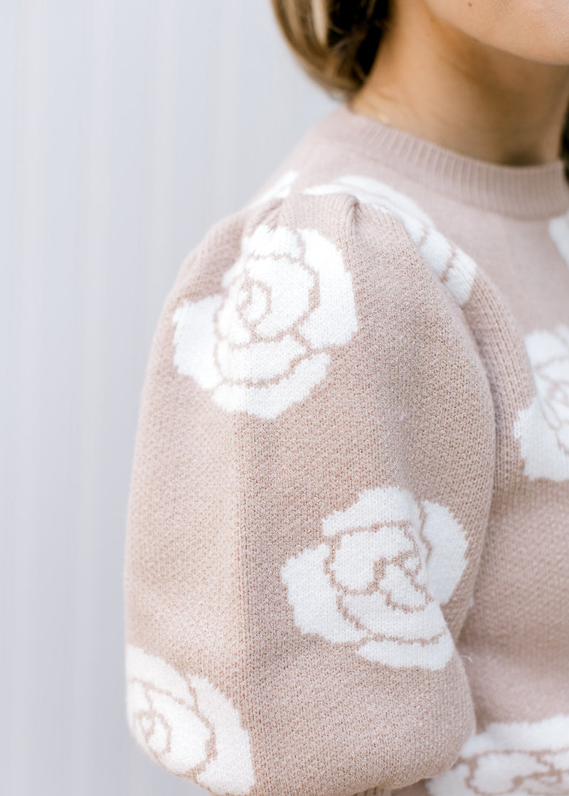 Close up of bubble short sleeve with pleated shoulder on a soft pink sweater with cream roses. 