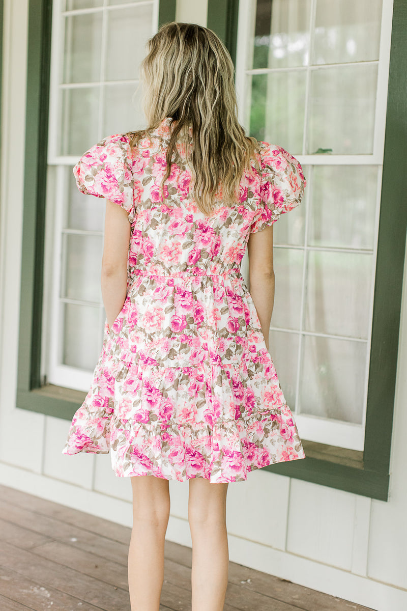 Back view of Model wearing a white dress with pink flowers and bubble short sleeves.