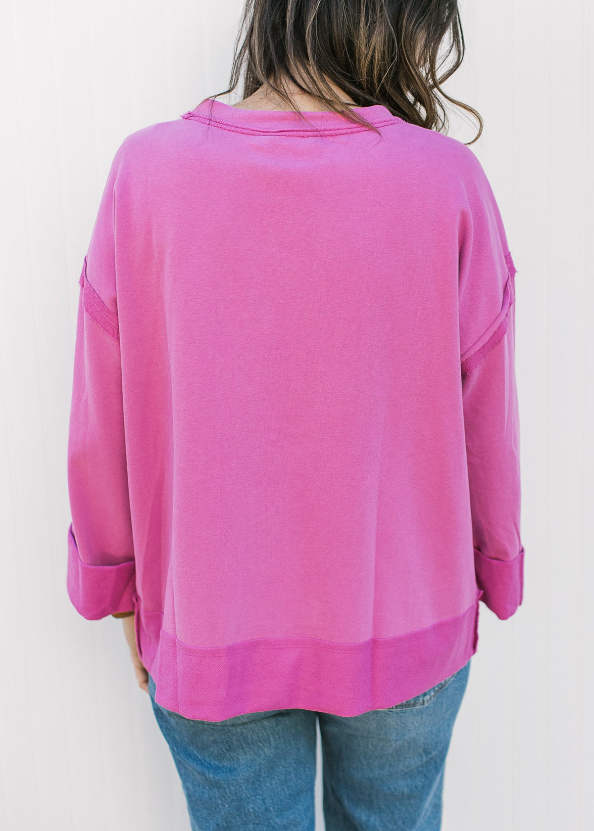 Back view of Model wearing a pink top with a stitched rose in the center and 3/4 sleeves. 