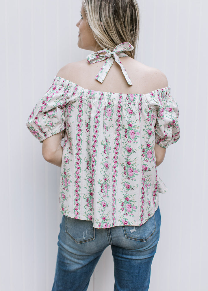 Back view of Model in a short sleeve cream top with pink floral stripes and elastic square neck.