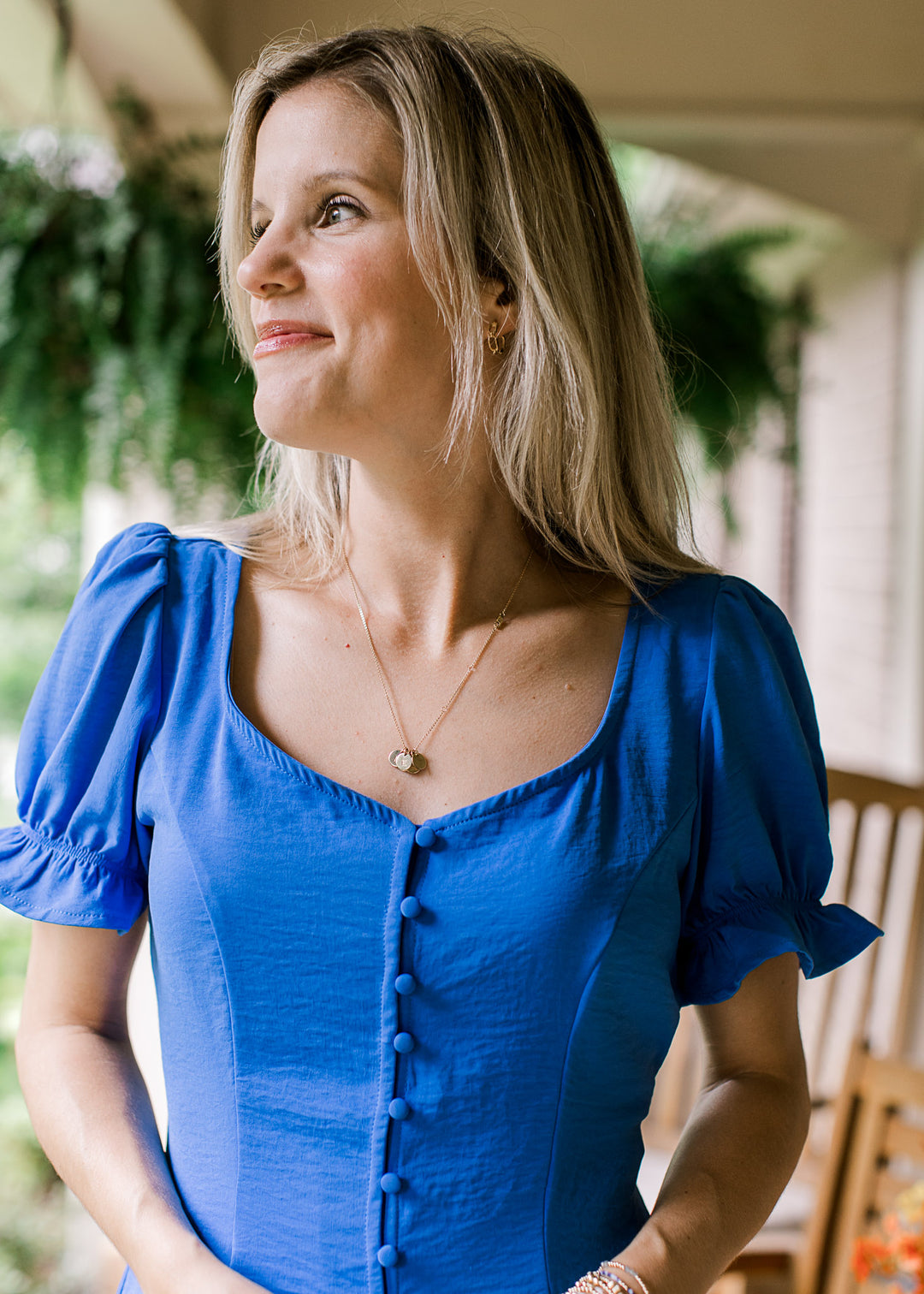 Model wearing a royal blue top with buttons, sweetheart neck and short sleeves with elastic cuffs.