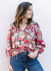 Model wearing a brown top with pink flowers, 3/4 sleeves and ruffle at neck and yolk. 