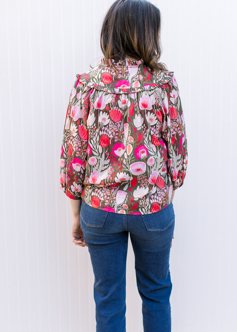 Back view of Model wearing a brown top with pink flowers, 3/4 sleeves and v-neck with a tie.