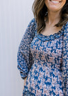 Close up of smocked bodice and ruffle detail around the neck of a navy maxi with cream flowers.