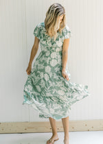 Model wearing a lined sage v-neck maxi dress with a cream floral design and a ruffle cap sleeve. 