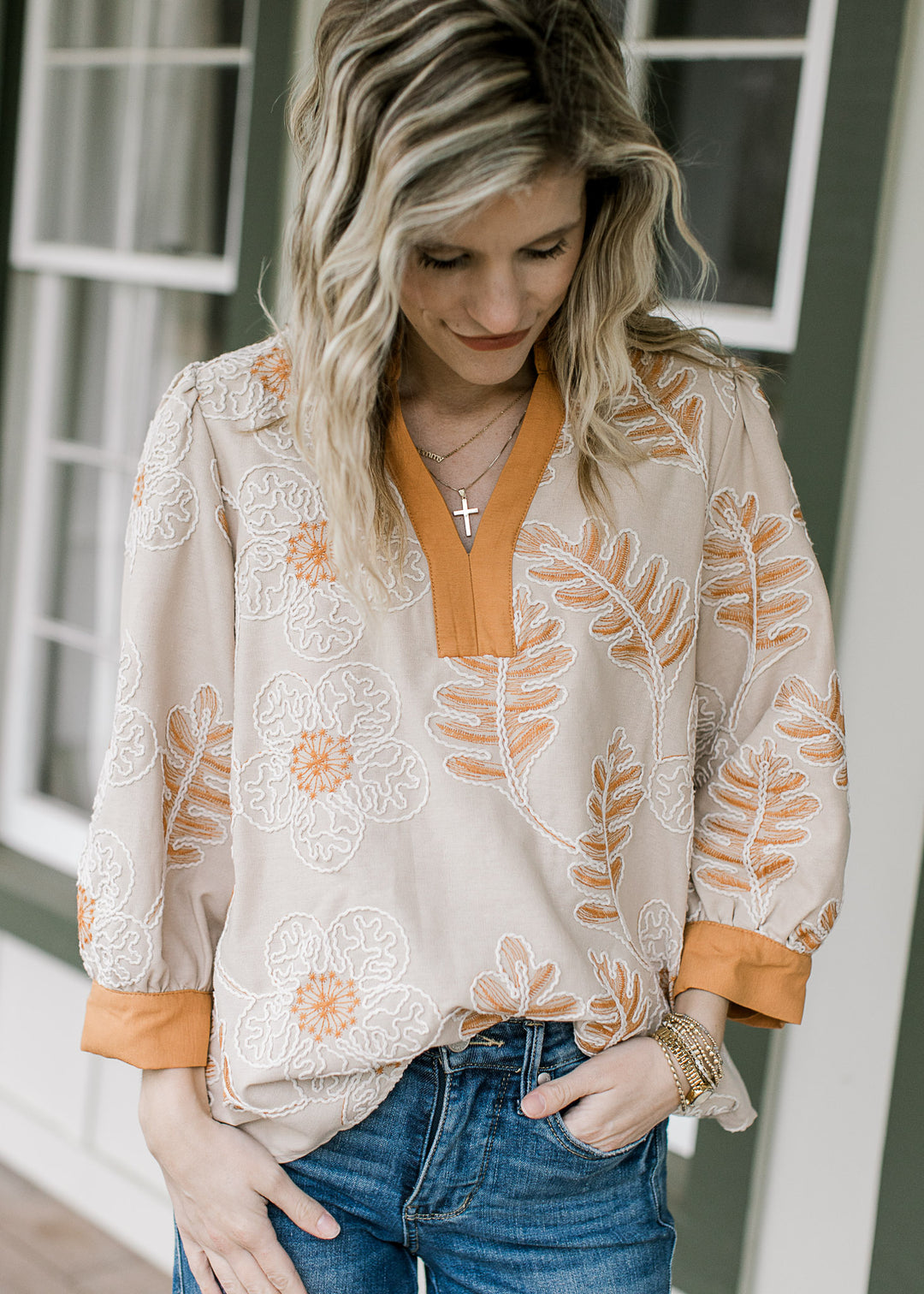 Model wearing a taupe blouse with cream and russet floral design, v-neck and 3/4 sleeves. 