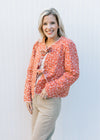 Model wearing khakis and a rust jacket with cream flowers, quilted material and two tie closure. 